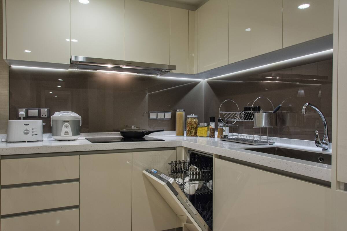 Una cocina moderna con lavavajillas, cocedor de arroz y un lavabo con escurreplatos.