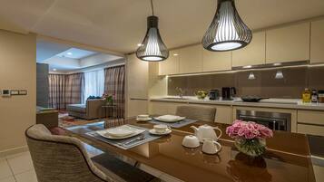 Una cocina moderna con comedor, que incluye una isla grande con superficie reflectante, dos lámparas colgantes y un florero con flores.