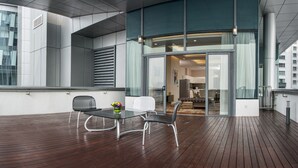 A modern outdoor seating area with a wooden deck, two chairs, a table, and a glass door leading to an interior space. - Ascott Sentral Kuala Lumpur (Kuala Lumpur)