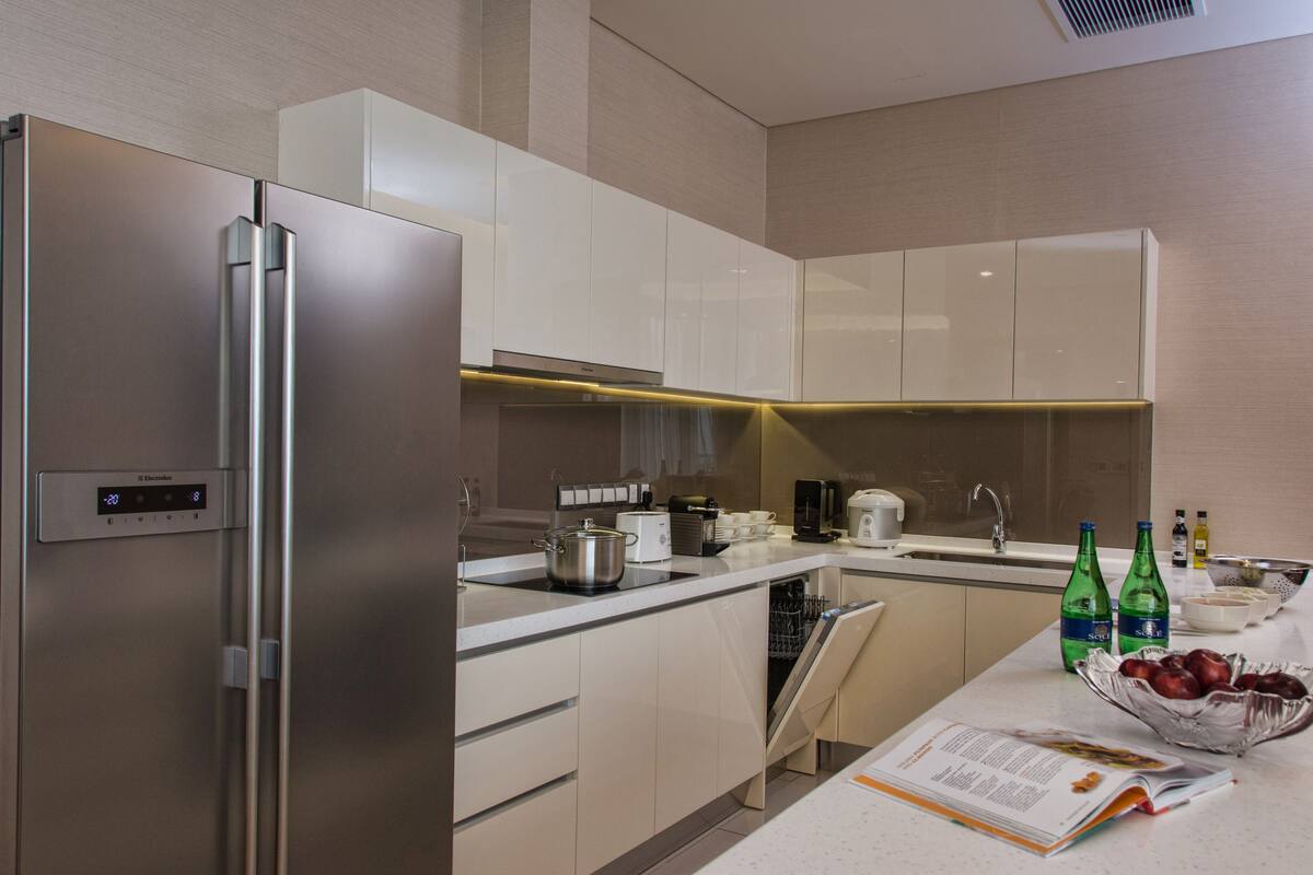 Una cocina moderna con electrodomésticos de acero inoxidable, armarios blancos y un diseño limpio y minimalista.