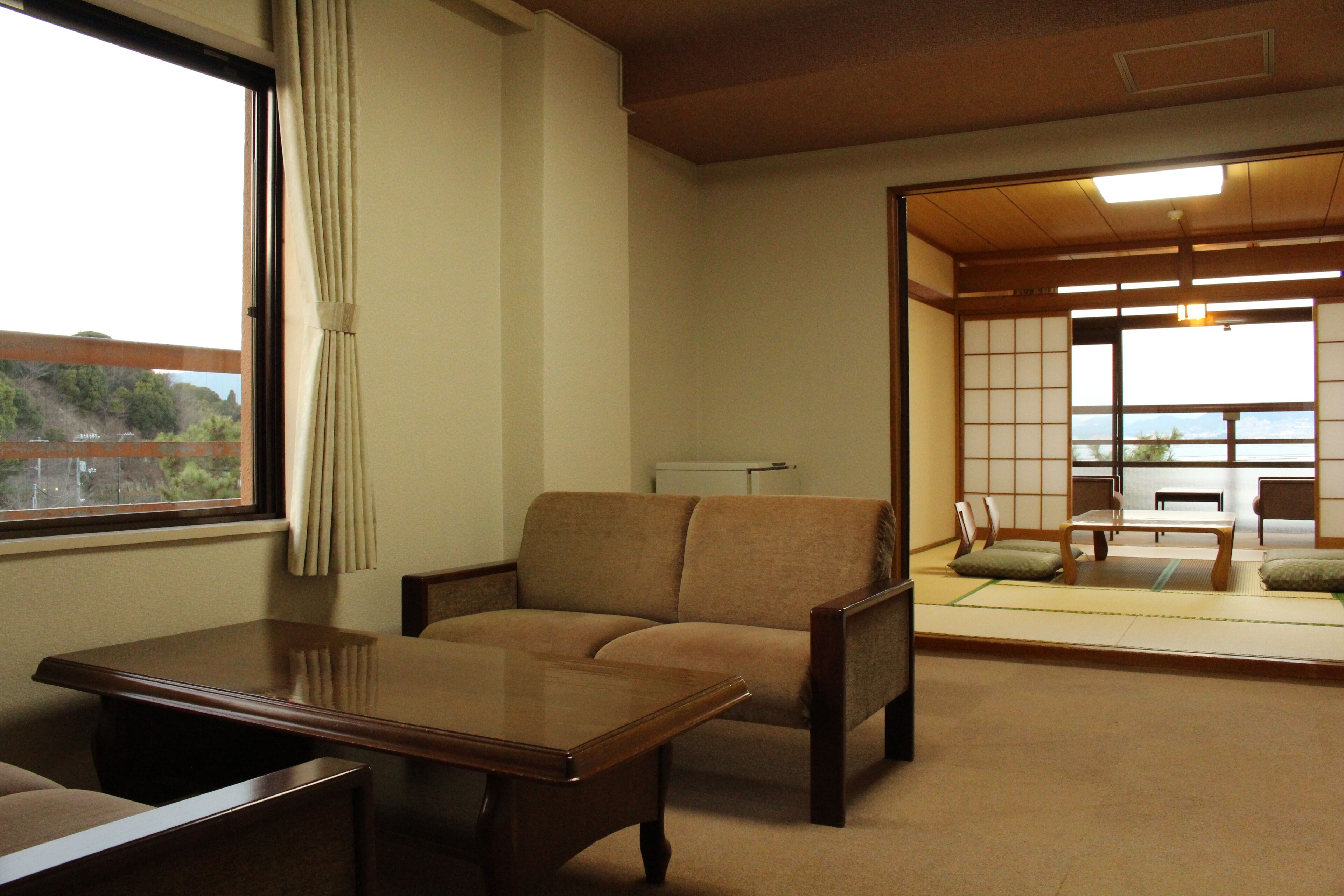 Una habitación tradicional japonesa con suelo de tatami, una mesa baja y un sofá.