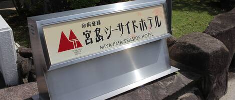 Un cartel del Hotel Miyajima Seaside con un logotipo rojo y texto en japonés.
