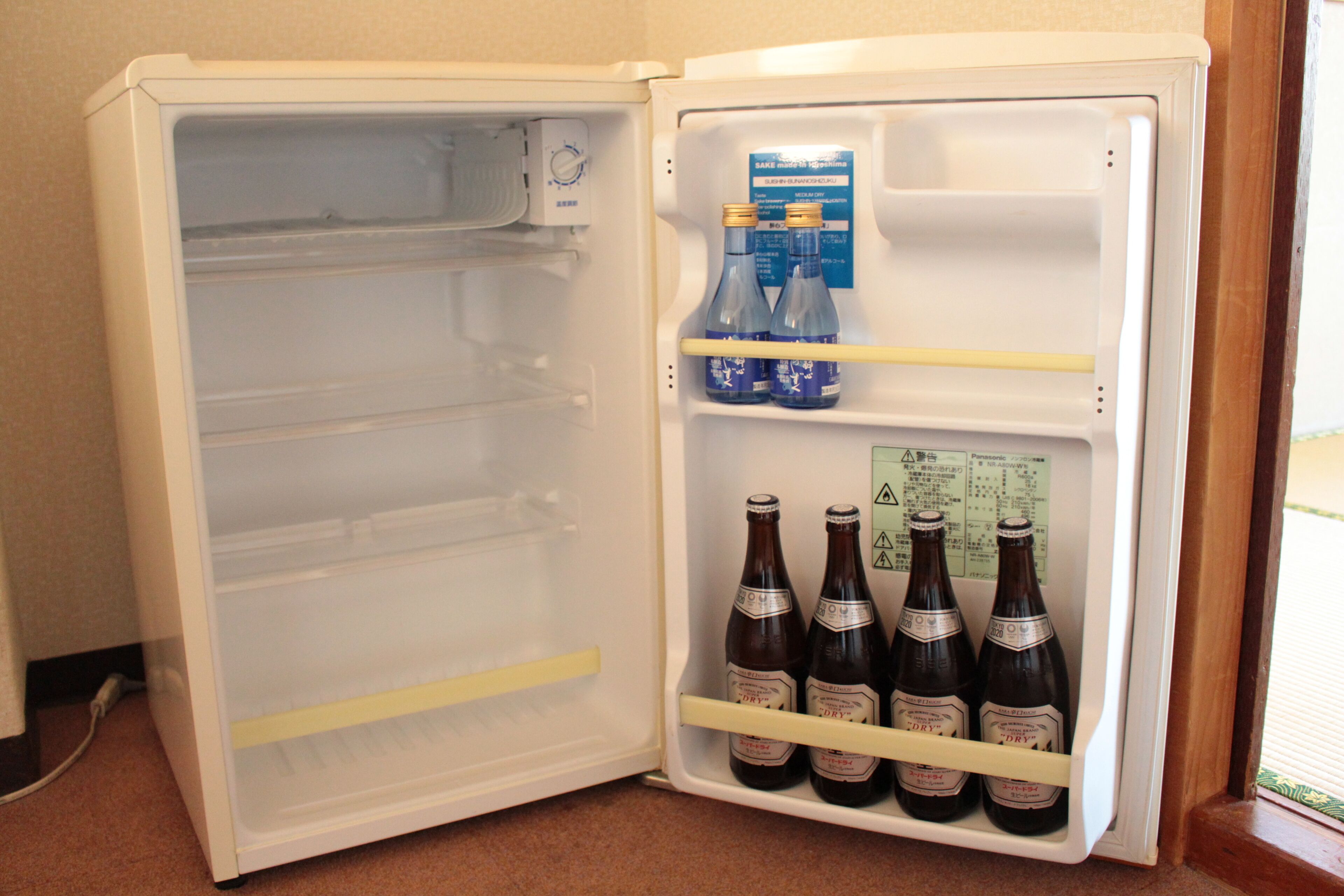 Ein offener Kühlschrank mit Regalen, auf denen Flaschen und eine Kiste stehen.