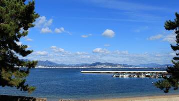 A coastal view with a pier extending into the water, surrounded by mountains and a clear sky.