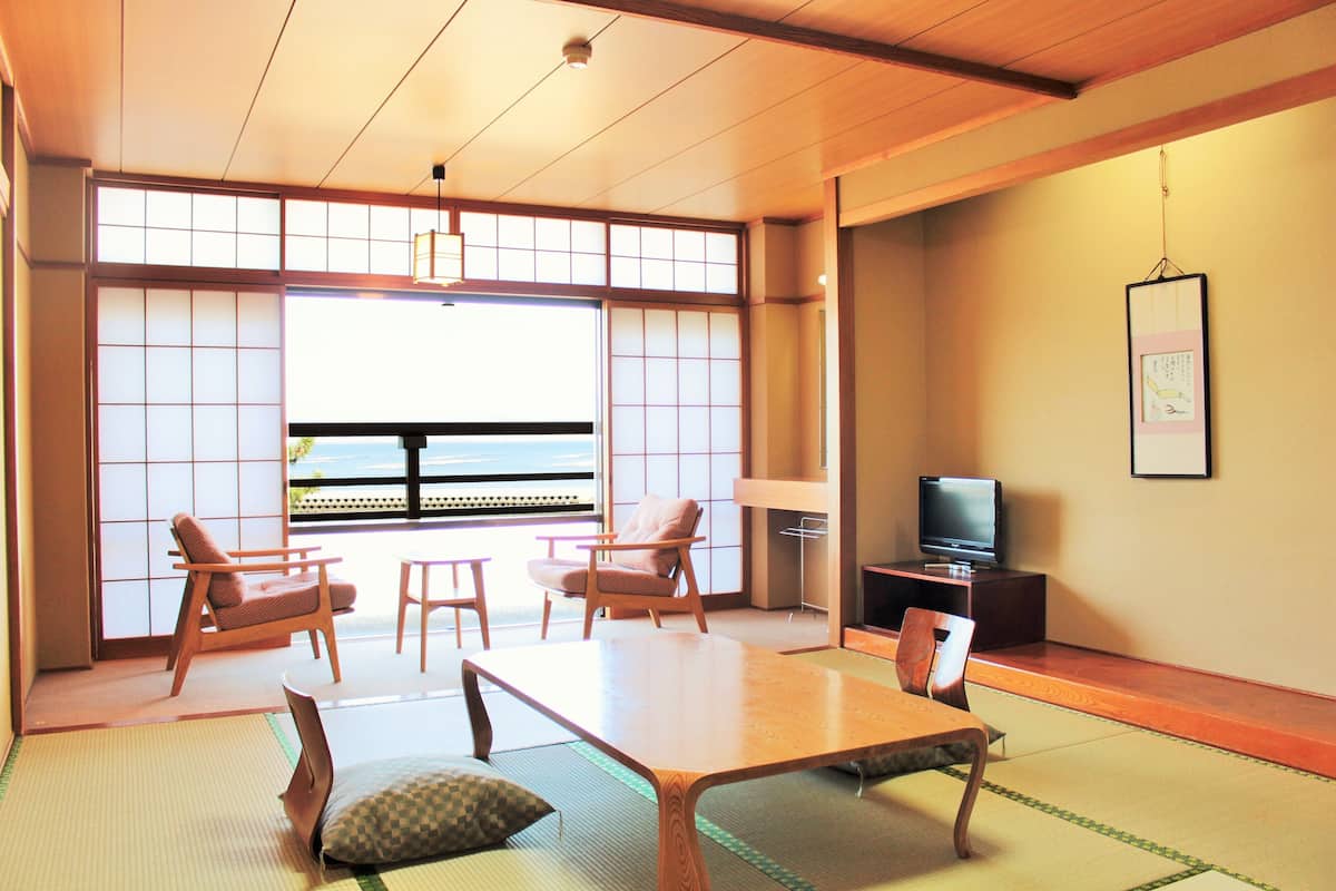 A traditional Japanese room with tatami flooring, a low table, and wooden chairs.