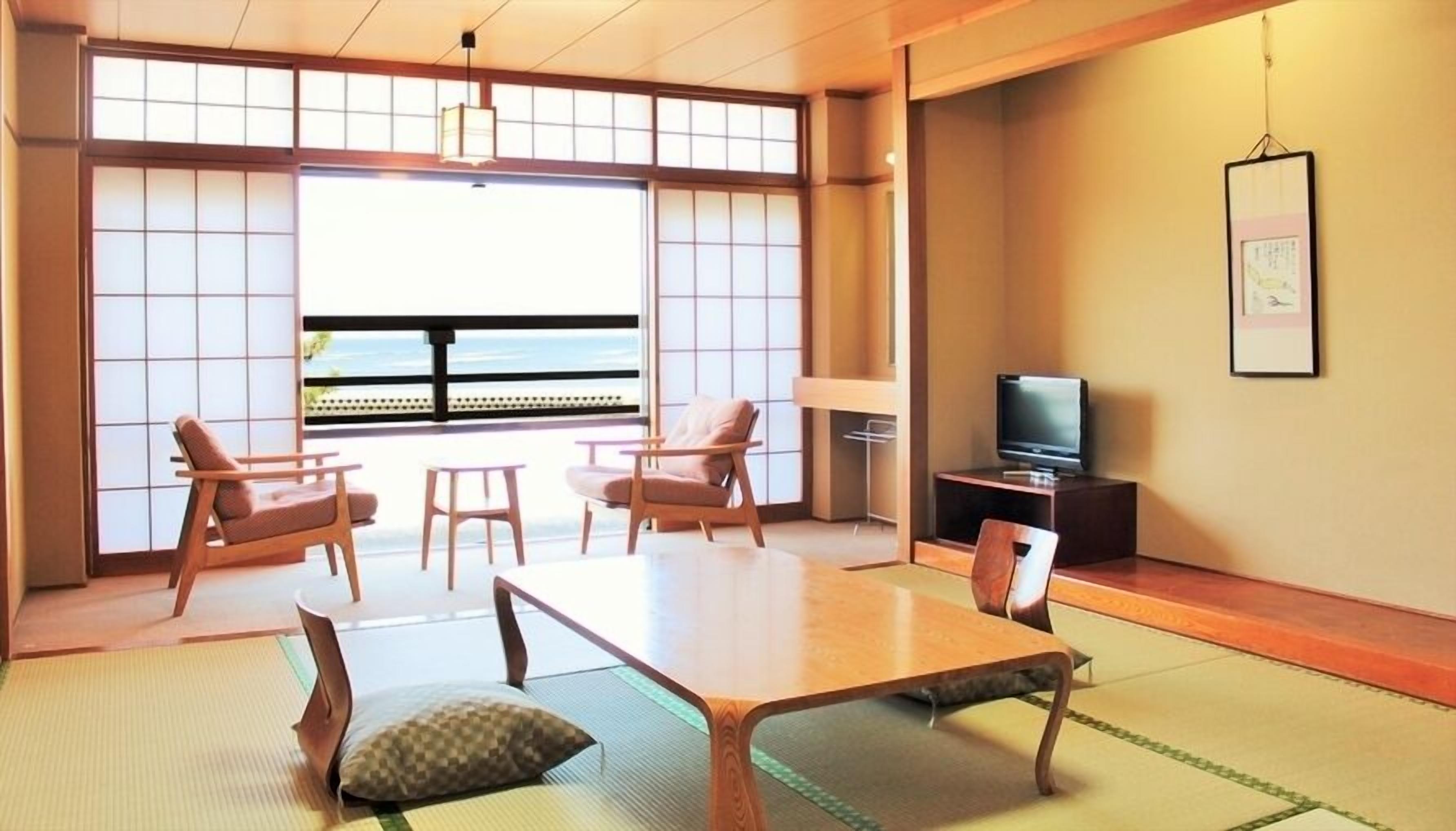 A traditional Japanese-style room with tatami flooring, a low table, and seating.
