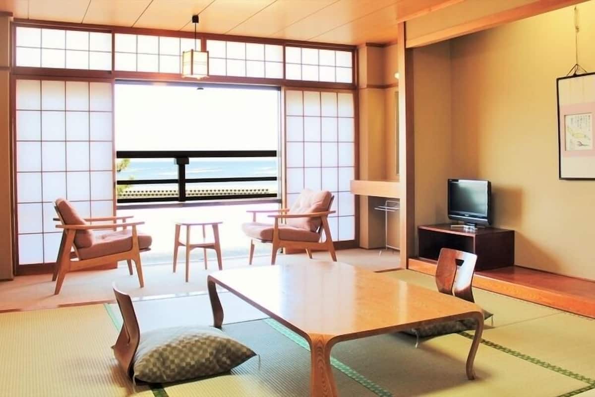 A traditional Japanese-style room with tatami flooring, a low table, and seating.