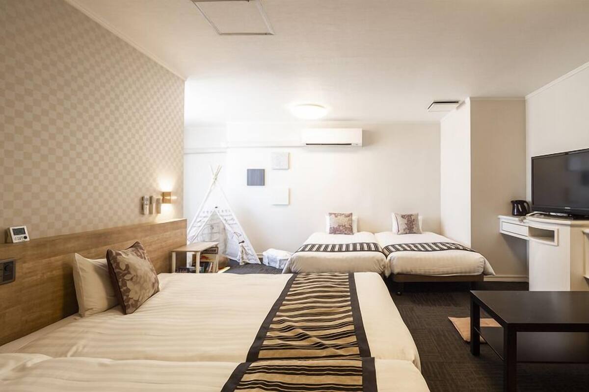 Habitación de hotel con dos camas, televisión, escritorio y una mesita.