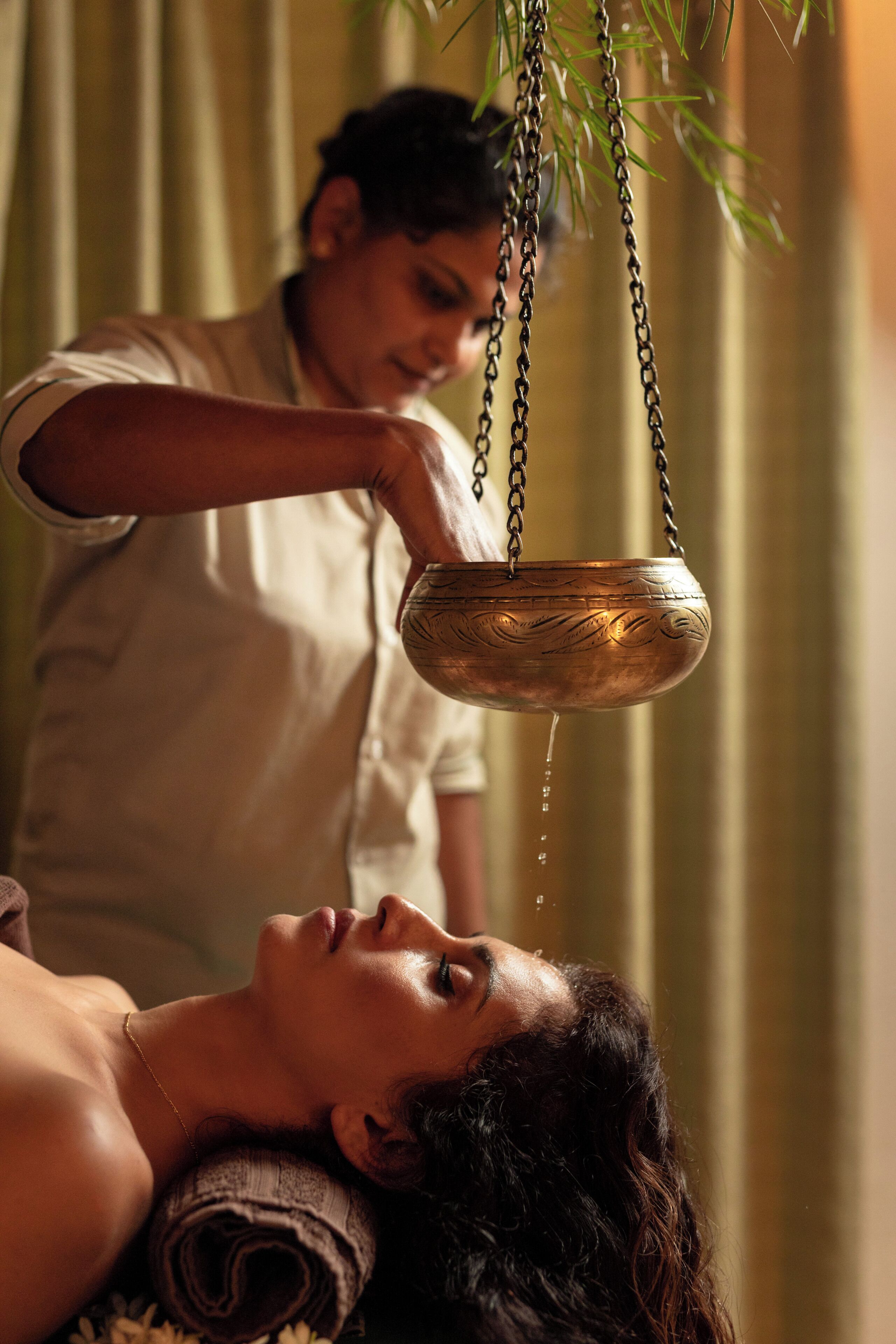 A person receiving a treatment with a hanging metal bowl.