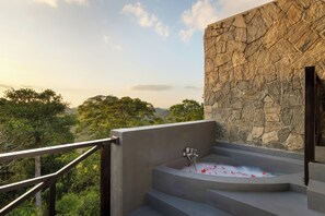 A stone wall, a bathtub with rose petals, and a view of trees. - Tree of Life Nature Resort (Harispattuwa)