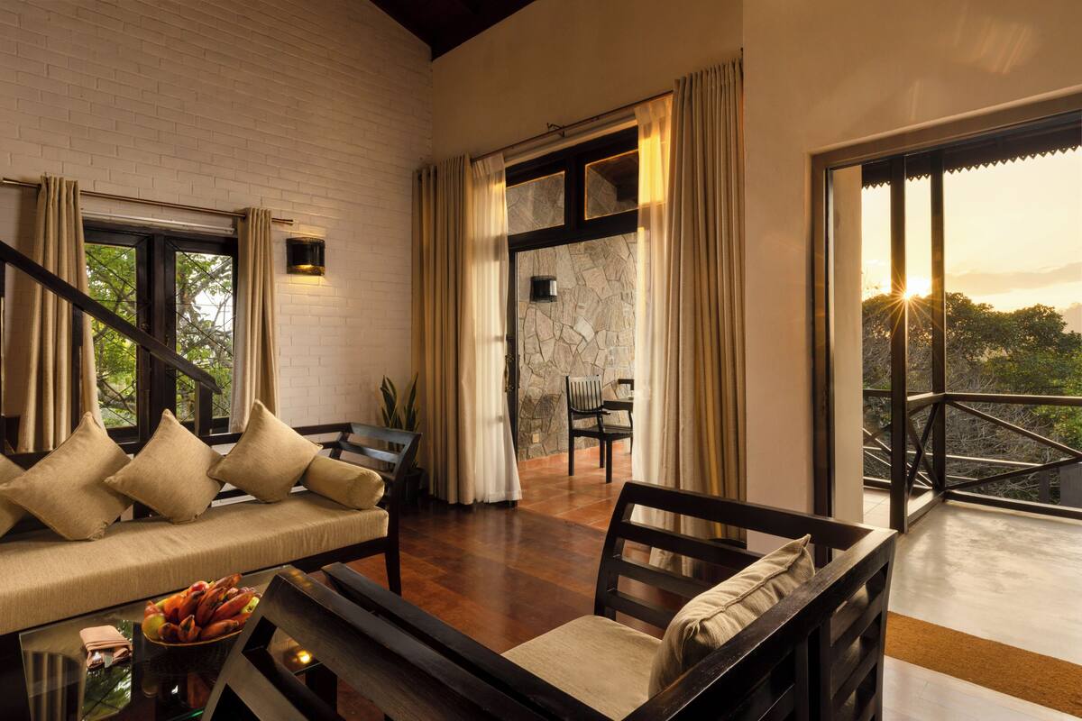 A modern interior with a sofa, chairs, a dining table, and a view through a large window.