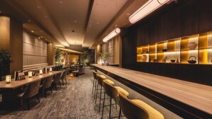 Un vestíbul d'hotel modern amb una llarga recepció, zona de bar i seients.