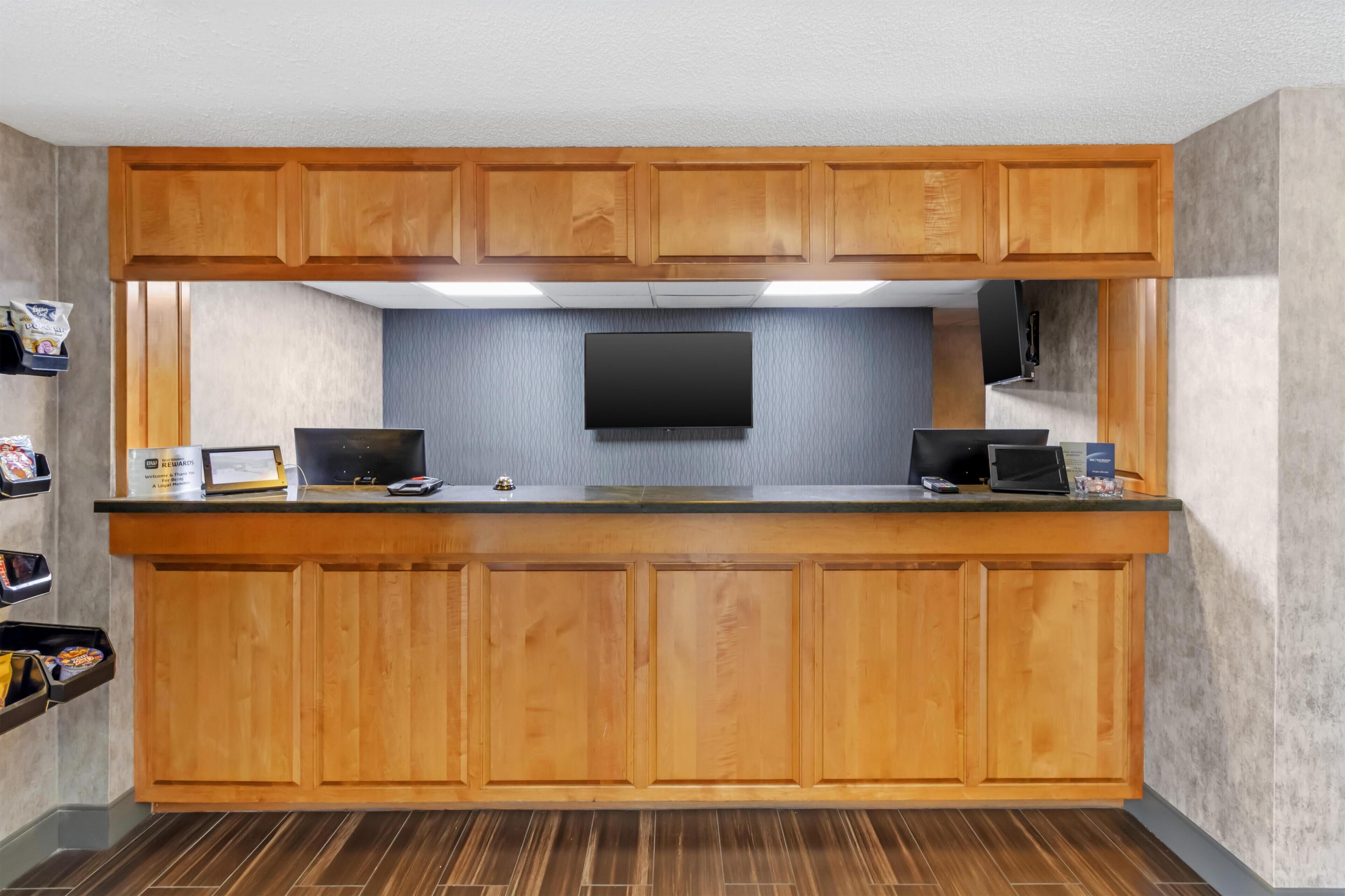 Une cuisine avec des meubles de rangement en bois, un plan de travail, un téléviseur à écran plat et un four à micro-ondes.