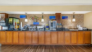A buffet-style breakfast area with a coffee station, juice dispensers, and a variety of food options. - Best Western University Inn (Murray)