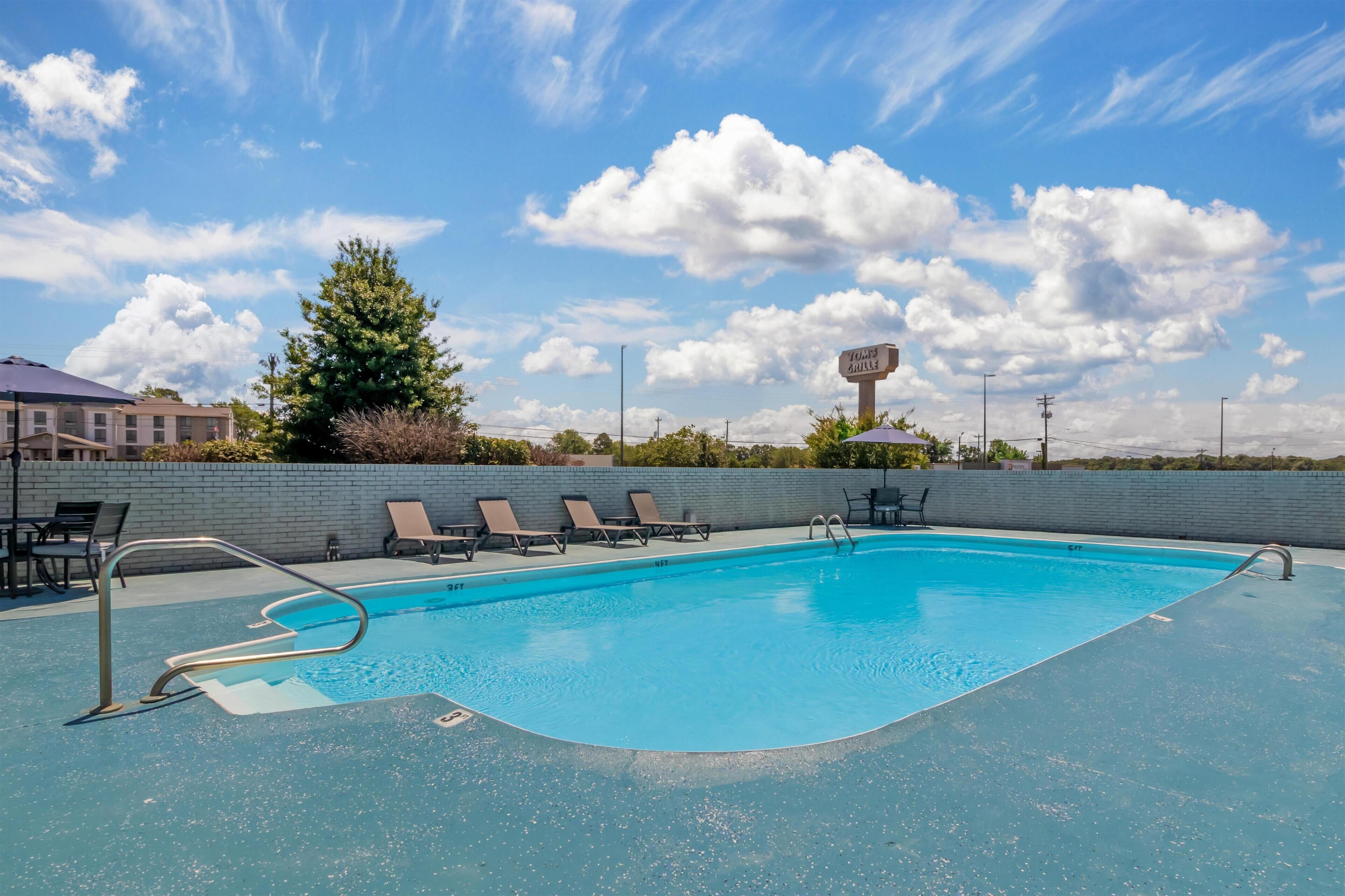 A swimming pool with lounge chairs and a sign in the background.
