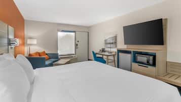A hotel room with a bed, a desk, a chair, a television, and a microwave.