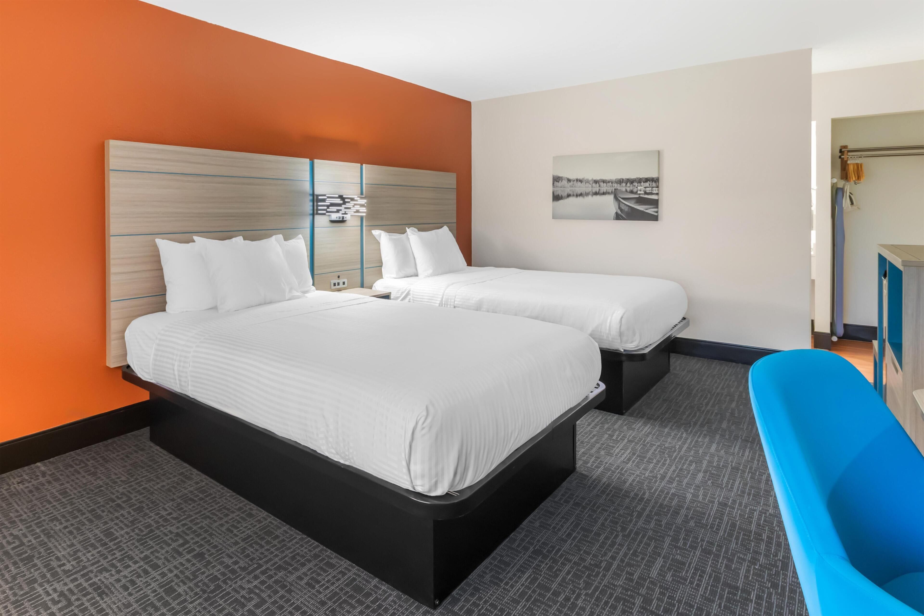 Une chambre d’hôtel avec deux lits, une baignoire bleue et un tableau accroché au mur.