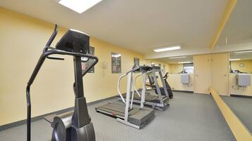 A gym with treadmills and elliptical machines, a mirror, and lockers.