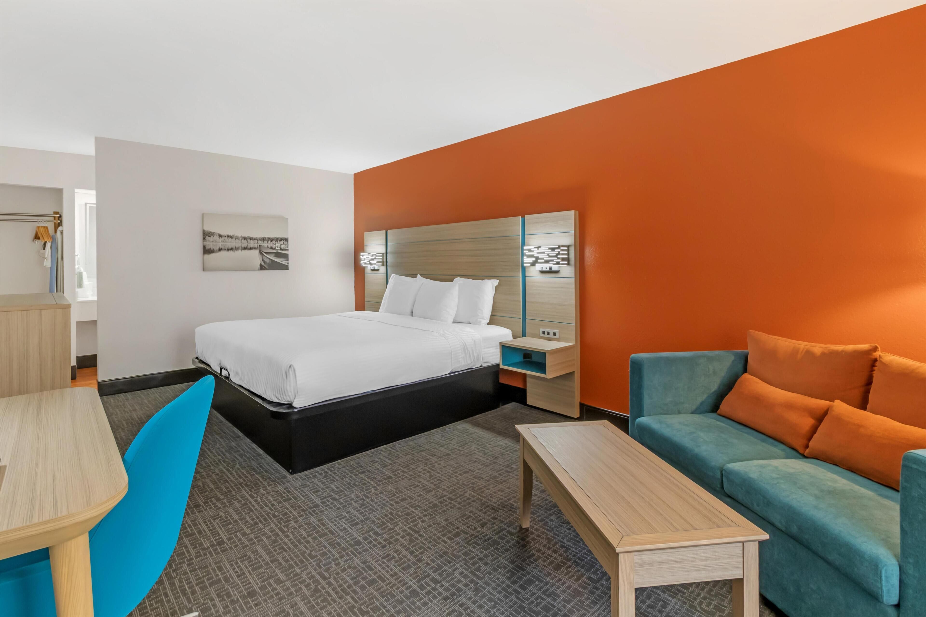 Une chambre d’hôtel comprenant un lit, un bureau, une chaise, un canapé et une table de chevet.