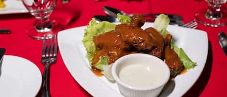 Un plato de comida con salsa y un recipiente pequeño con salsa sobre un mantel rojo.