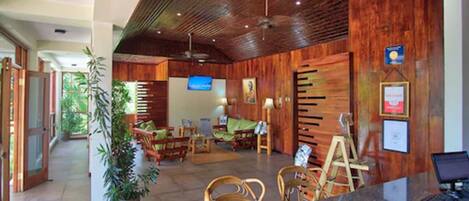 A reception area with wooden paneling, a reception desk, a television, and a large potted plant.