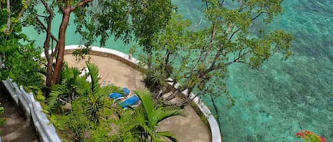 Un complexe hôtelier tropical offrant une vue dégagée sur la mer turquoise, entouré d’une végétation luxuriante et bordé d’une plage de sable fin.