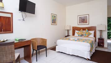 Habitació d'hotel amb llit, escriptori, cadira, televisió i obres d'art a les parets.