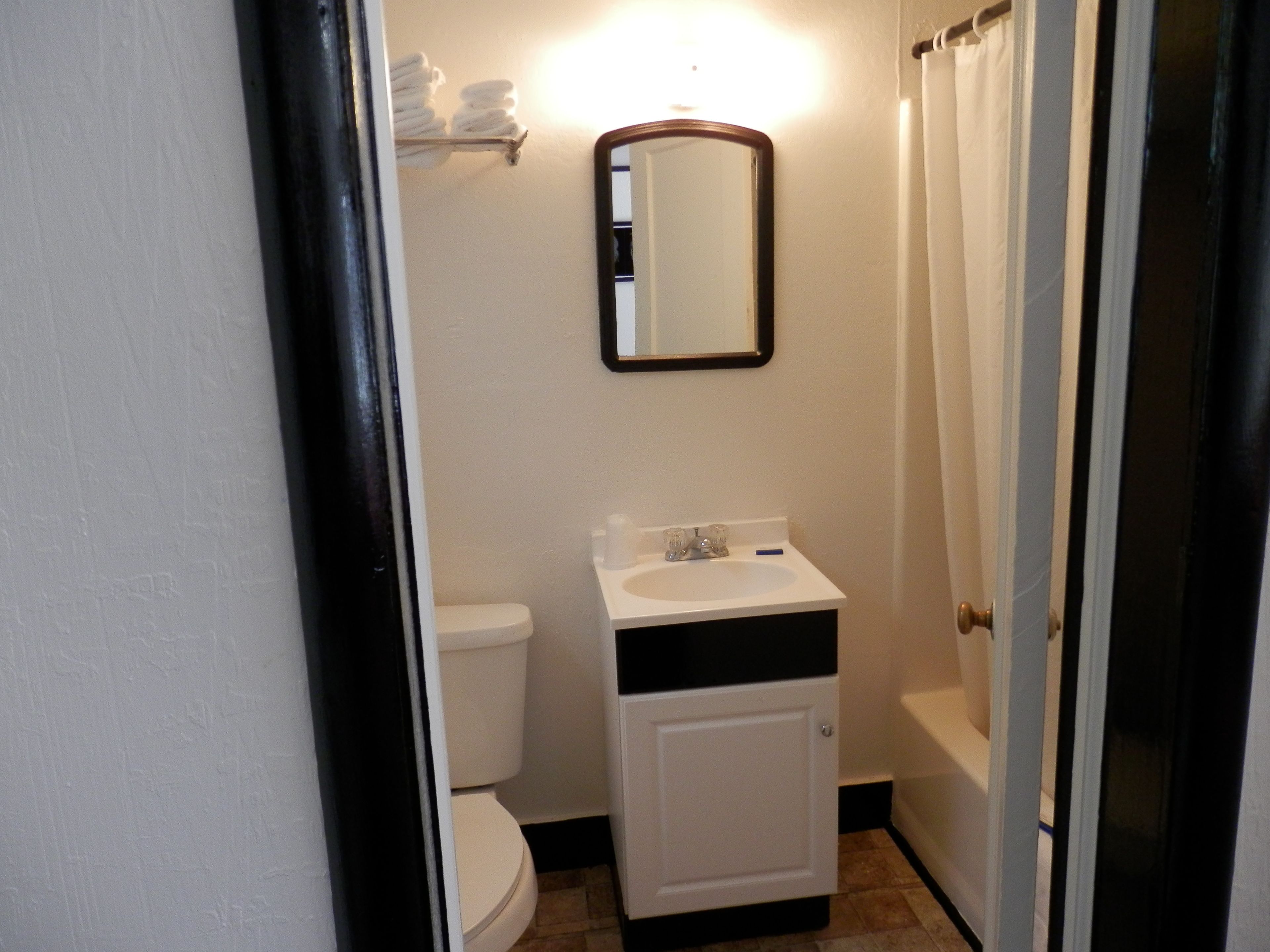 A small bathroom with a toilet, sink, and a mirror.