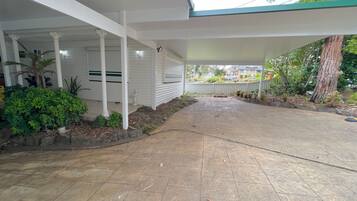Un espace extérieur abrité, doté d’un sol carrelé, de colonnes blanches et d’une variété de plantes.