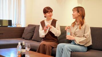 Two people sitting on a couch with a table in front of them holding drinks.