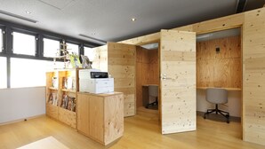 A modern office space with wooden walls, a reception desk, and office chairs. - Hotel Naturwald Furano (Furano)