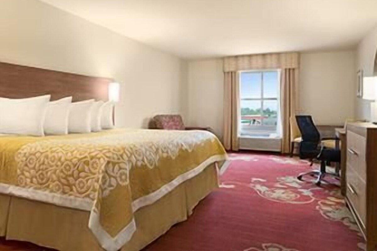 A hotel room with a bed, a desk, a chair, and a window with a view.