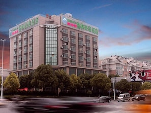 A multi-story hotel with a modern design, featuring a prominent glass facade and multiple air conditioning units.