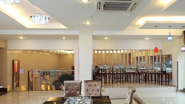 A hotel lobby with a central dining area, a staircase, and a reception desk. - GreenTree Inn Taizhou Gaogang District Gov. Business Hotel (Taizhou)