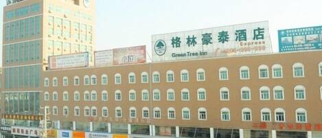 Un hotel con varios pisos, un llamativo letrero de Green Tree Inn y varias tiendas en la fachada.