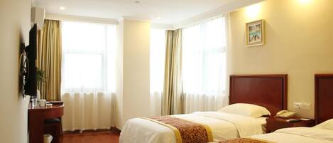 A hotel room with two beds, a desk, a chair, a small table, a telephone, and a picture on the wall.