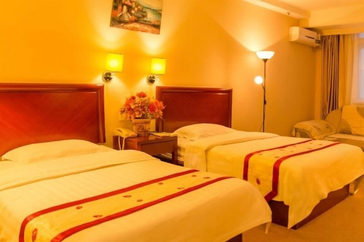 Una habitació d'hotel amb dos llits, una nitòria amb una làmpada i un quadre a la paret.
