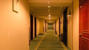 Pasillo de hotel con pisos alfombrados, puertas de madera y un largo corredor que lleva a una habitación.