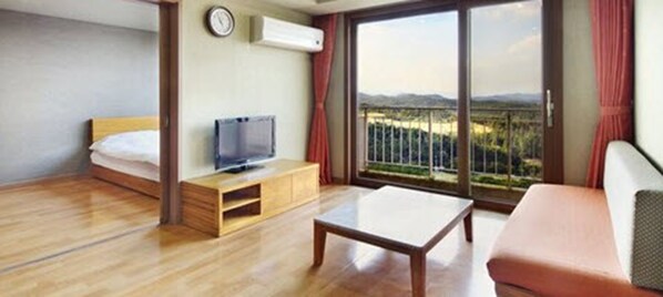 Una habitación de hotel con una cama, un televisor sobre un mueble de madera, una mesita de centro y un sofá.