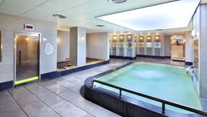 Un espace piscine intérieur moderne, doté d’une horloge numérique, de plusieurs lavabos et d’une verrière.