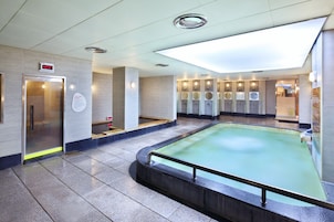 Un área de piscina interior moderna con un reloj digital, varios lavamanos y un tragaluz.