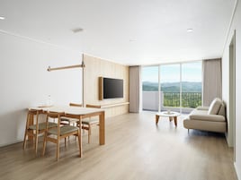 Una sala moderna con comedor, televisor de pantalla plana en la pared, balcón con vistas a las montañas y un sofá.