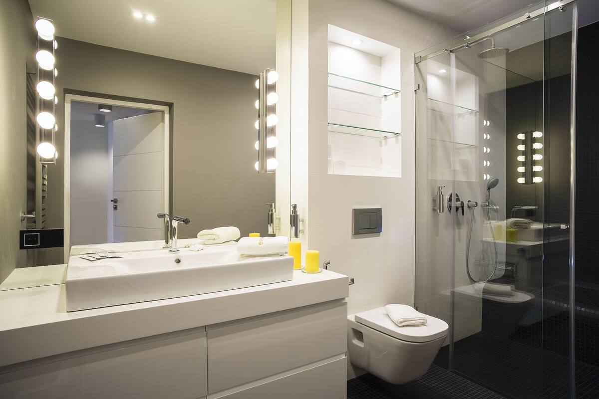 A modern bathroom with a large mirror, vanity, and a glass shower enclosure.