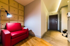 Una sala de estar moderna con un sofá rojo, una lámpara de pie y un aplique de pared.