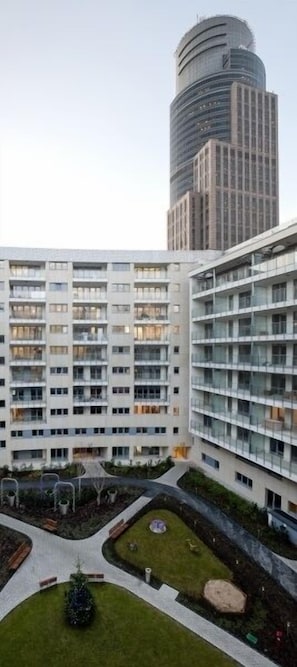 Un moderno edificio de apartamentos con varios pisos, balcones y un patio central con vegetación y zonas de estar.