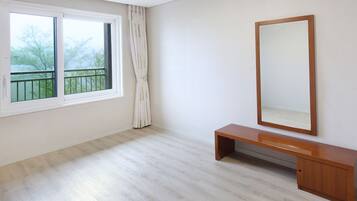 A room with a large window, a wooden bench, and a mirror on the wall.