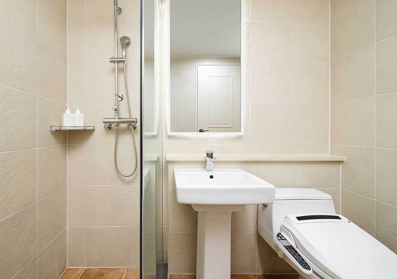Een badkamer met douche, wastafel en toilet.