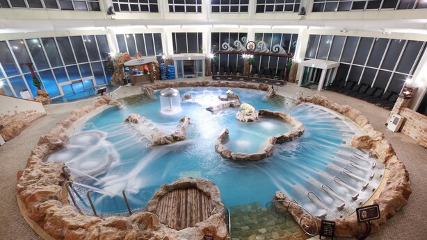 An indoor swimming pool with multiple water features, seating areas, and a high ceiling with natural light. - Hanwha Resort Seorak Sorano (Sokcho)