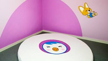 A room with a white toilet, a pink wall, and a cartoon character on the wall.