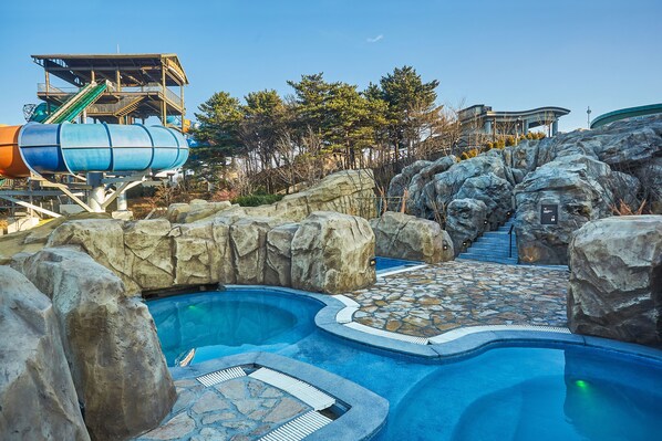 A water park with a pool, rock formations, and a water slide.